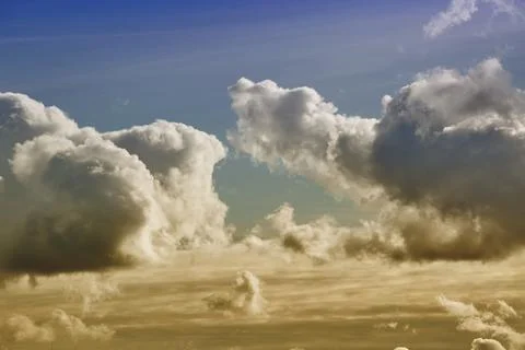 Cumulus clouds in the warm evening light cover the sky. Stock Photos