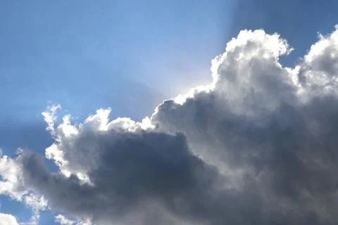 Cumulus gray clouds, clouds blocking sun in blue sky, sunlight from behind .. Stock Photos