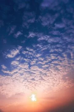 Cumulus sunset clouds with sun setting down Stock Photos