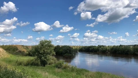 Cumulus white clouds float over the blue sky, and under them the river Om Stock Footage 93035001