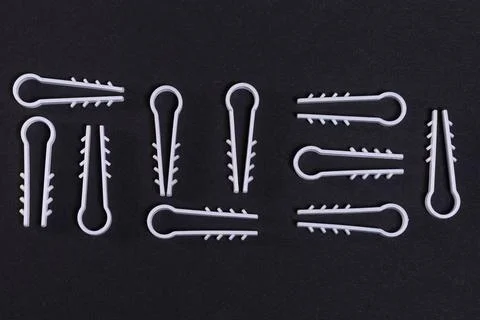 Cuneiform pattern of white, plastic fastening clips on black paper Stock Photos