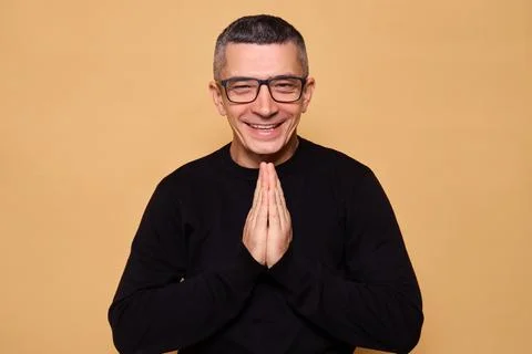 Cunning man wearing glasses and black jumper gesticulating with his hands p.. Foto stock