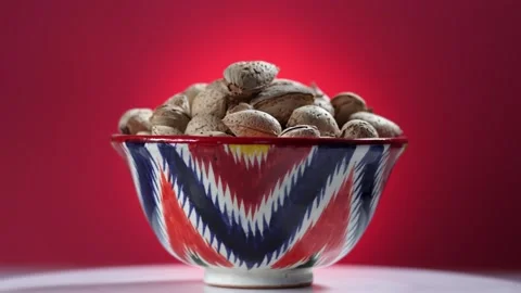 A cup with almonds rotates on a red background Stock Footage 159145787