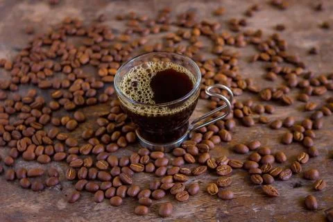 Cup and coffee beans on a table Stock Photos