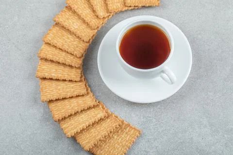 A cup of aroma tea with crackers on a gray background Stock Photos