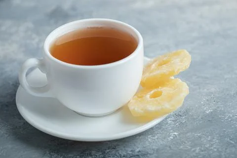 A cup of aroma tea with dried pineapple on a dark background Stock Photos