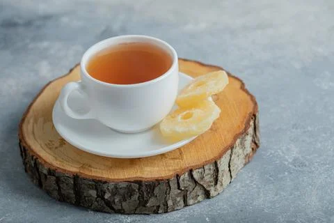 A cup of aroma tea with dried pineapple on a dark background Stock Photos
