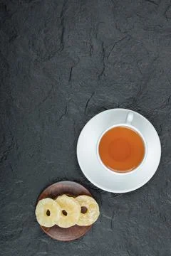 A cup of aroma tea with dried pineapple on a dark background Stock Photos