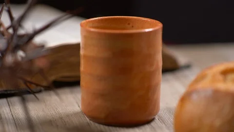 Cup being filled with wine with Crown of Thorns and old Bible and bread 스톡 동영상 128556457