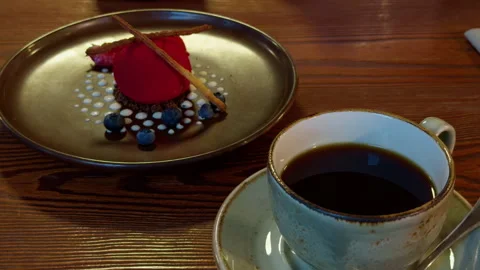 Cup of black coffee beside elegant berry dessert on rustic wooden table in warm Stock Footage 345766264