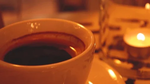 Cup of black coffee with a candle in a coffee shop in the evening Stock Footage 101533176