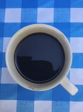 A cup of black coffee on checked plastic tablecloth Stock Photos