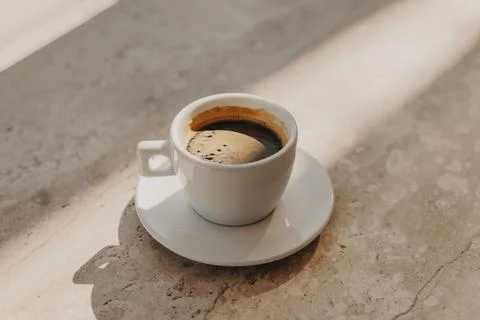 Cup of black coffee on a marble table in a cafe in a sunlight. Natural warm.. Foto stock