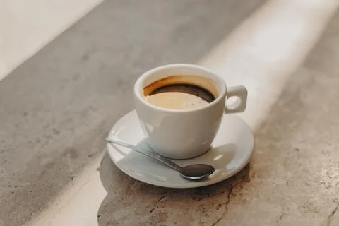 Cup of black coffee on a marble table in a sunlight. Natural warm colors. Foto stock