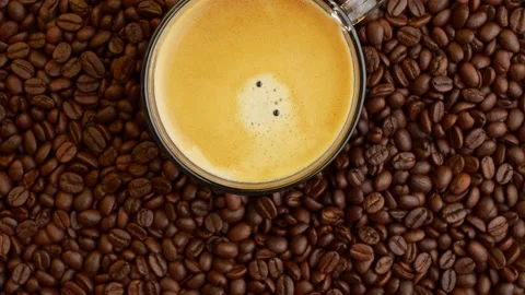 Cup Black Coffee On Rotating Roasted Coffee Beans Background. Stockbeeldmateriaal 195784447