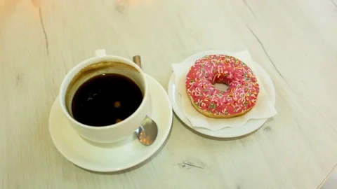 Cup of black coffee started and donuts are on the table. Medium shot, top view, Stock Footage 85102614