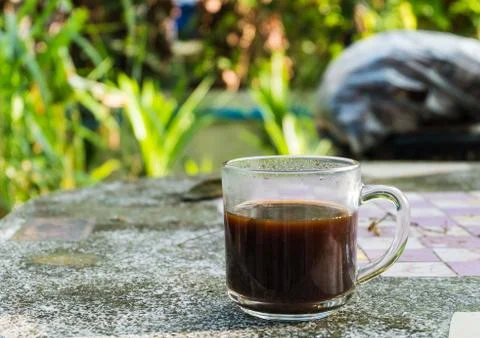Cup of black coffee on the stone table and green leaf background Stock Photos