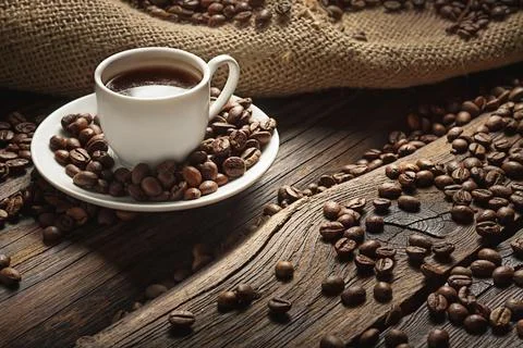Cup of Black Coffee Surrounded by Roasted Beans on Rustic Wooden Table Stock-Fotos