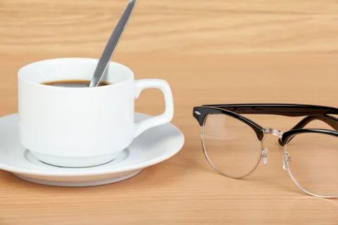 Cup of black coffee on table with eye glasses Stock Photos