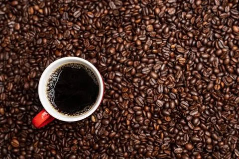 Cup of black coffee from the top on background covered with coffee beans. Stock Photos