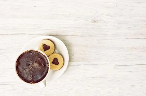 Cup of black coffee with two jam biscuits in the shape of heart on the wooden Stock Photos