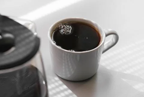 Cup of black coffee on a white table under the sunlight of the morning Stock Photos