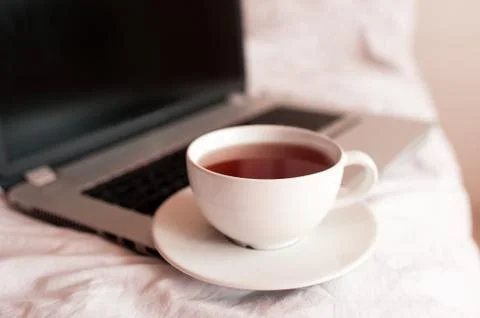 Cup of black tea on computer in bed closeup. Good morning. Breakfast time. So Stock Photos