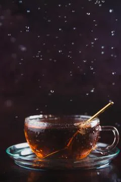 Cup of black tea on dark background with water or rain drops falling into it, Stock Photos