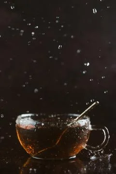 Cup of black tea on dark background with falling water or rain drops, selecti Stock Photos