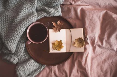 Cup of black tea with open note book on wooden tray and knitted sweater in be Stock Photos