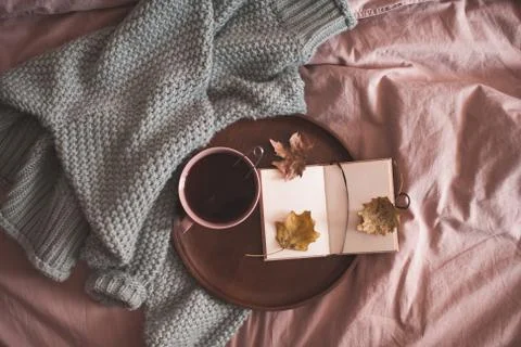 Cup of black tea with open note book on wooden tray and knitted sweater in be Stock Photos