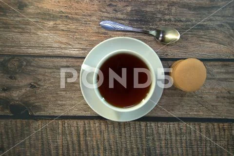 A cup of black tea on a porcelain saucer, a spoon and a stack of sponge cooki Stock Photos