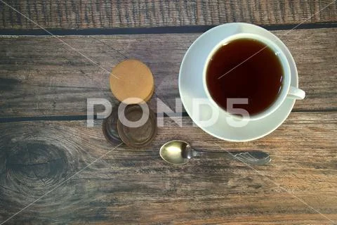 A cup of black tea on a porcelain saucer, a spoon and a stack of sponge cooki Stock Photos