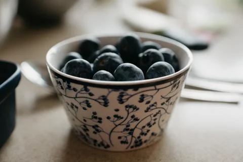A cup of blueberries is on the table in the kitchen. Stock Photos