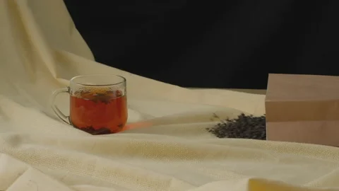 A cup of brewed black tea and tea leaves spilling out of a paper bag.Slow motion 스톡 동영상 204154267