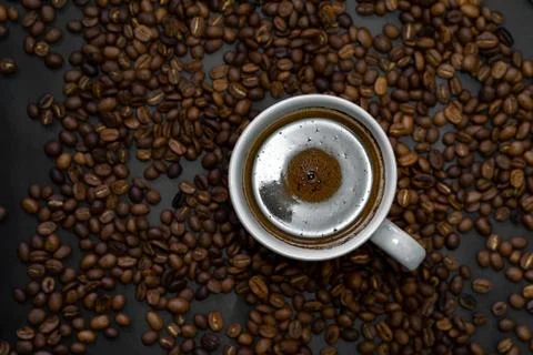 A cup of brewed coffee is served on roasted coffee beans. Foto stock