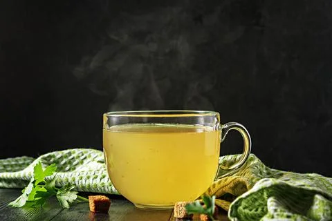 Cup with broth on a dark background with steam. Stock Photos