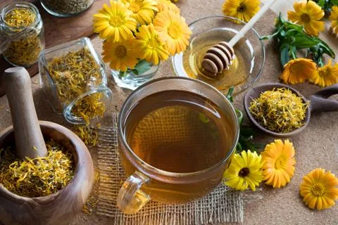 A cup of calendula tea with calendula in the background Stock Photos