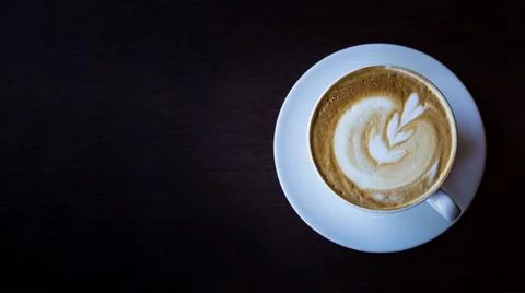 A cup of cappuccino with pattern in cup on dark background. Banner. Stock Photos