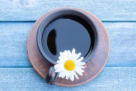 A cup of chamomile tea and chamomile flowers on wooden blue background. Stock Photos