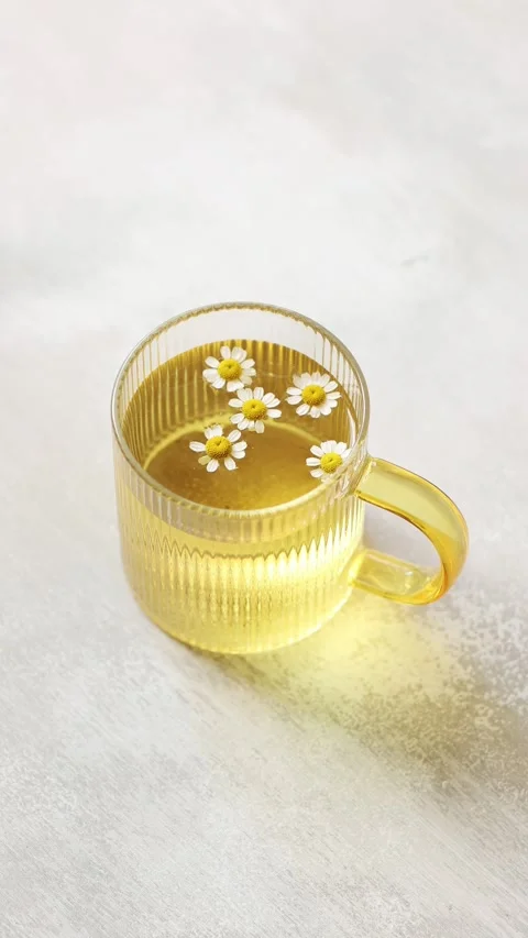 A cup of Chamomile tea on light wooden table with flowers Stock Footage 246324979