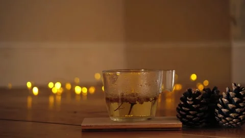 Cup of chamomile tea with pine cones with twinkling lights bokeh Stock Footage 295618947