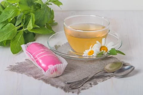 Cup of chamomile tea with pink eclair Stock Photos
