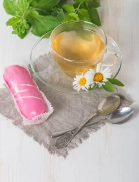 Cup of chamomile tea with pink eclair Stock Photos