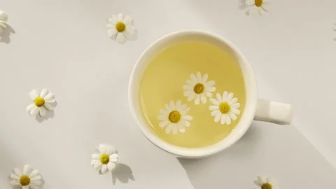 A cup of chamomile tea on a white background with flower buds inside. Stock Footage 171546430
