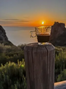 A cup of coffee against the backdrop of the setting sun Stock Photos