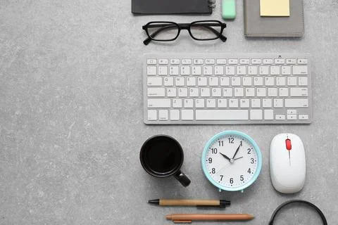 Cup of coffee, alarm clock, computer keyboard and mouse on grey grunge backgr Stock Photos