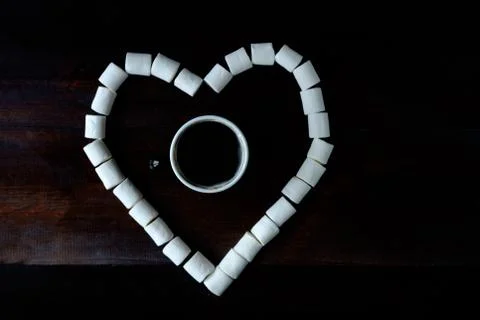 Cup of coffee among marshmallows in shape of heart on wooden dark surface Stock Photos