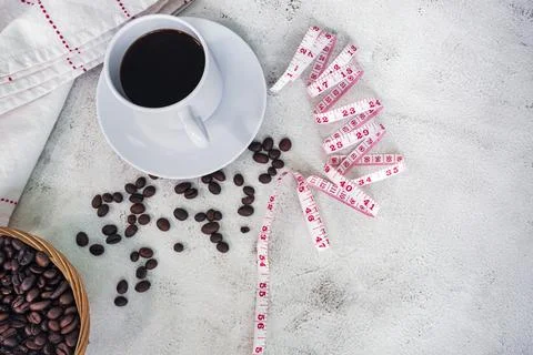 Cup of coffee and coffee beans background with measure tap on white desk. Foto stock