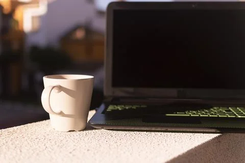 Cup of coffee and computer in the sun Stock Photos